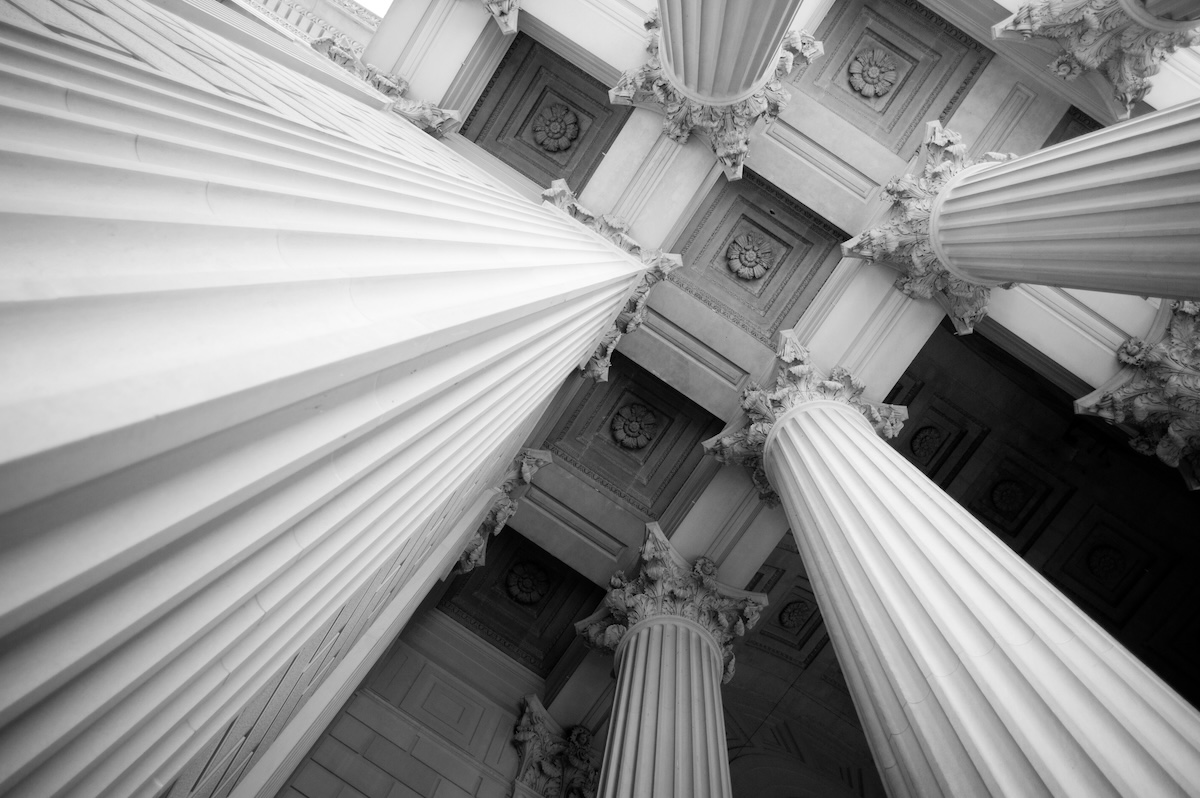 Photo shows a view of big marble columns reaching for the ceiling.